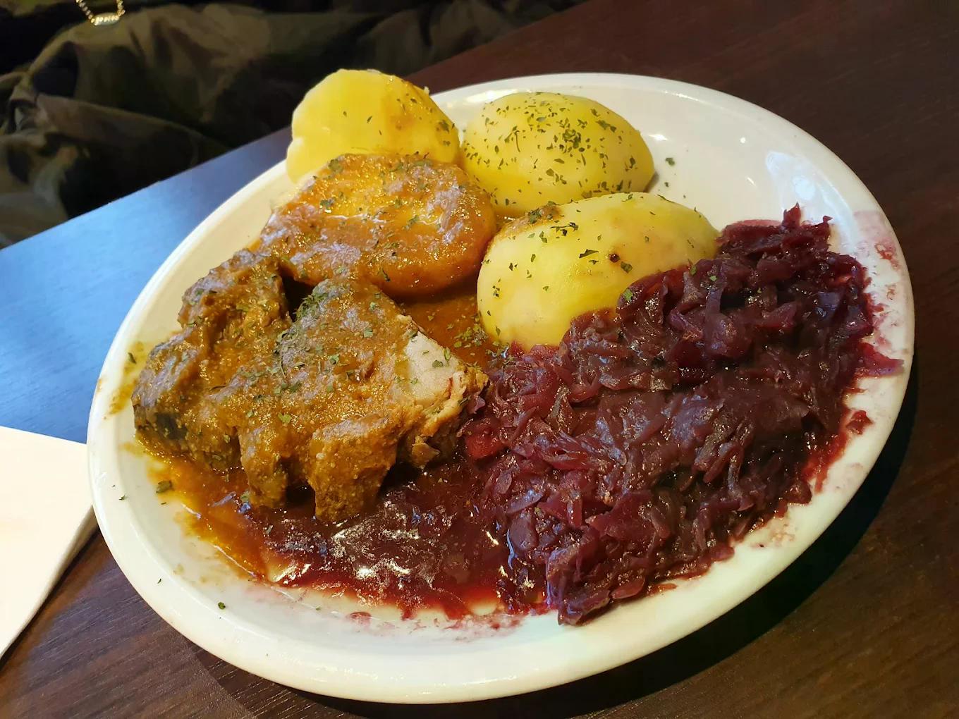 Ein Teller mit Kartoffeln, Rotkohl und saftigem Fleisch in brauner Sauce